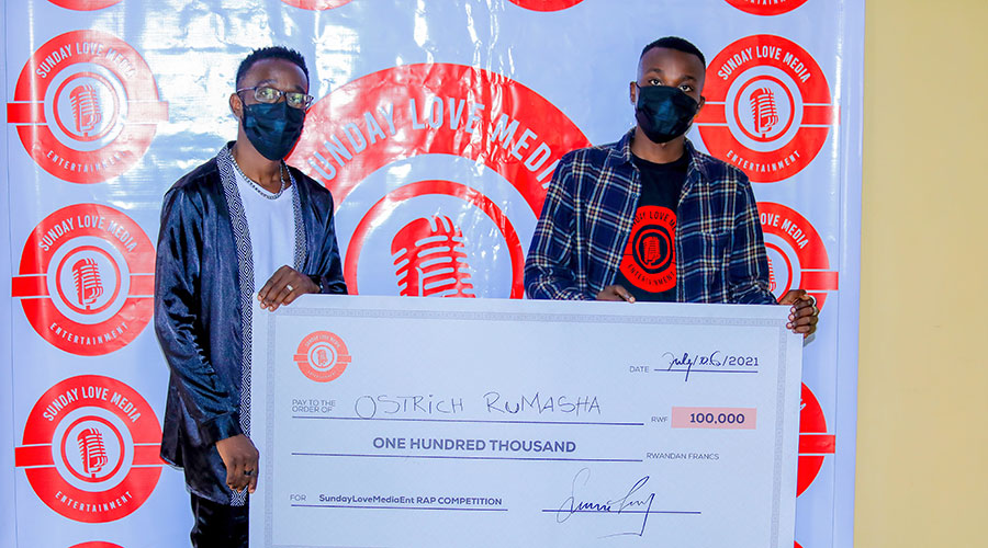 Sunday Justin Nzitatira (left) handing a dummy cheque to the winner. 