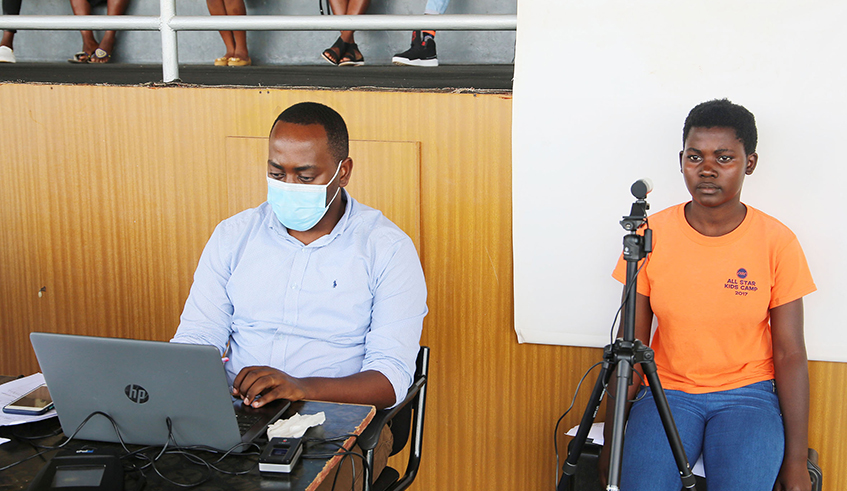 A young girl is photographed by an employee of the National Identification Agency at Amahoro Stadium on Monday, September 27. / Photo: Craish Bahizi.