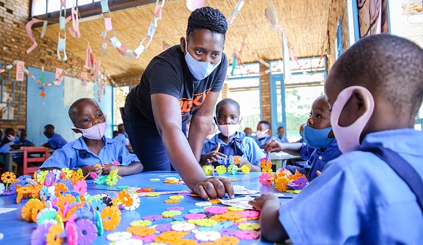 A teacher helps young pupils during a drawing lesson at Nyarugunga Early Childhood Development Centre in Kicukiro District on June 28, 2021. / Photo: Dan Nsengiyumva.