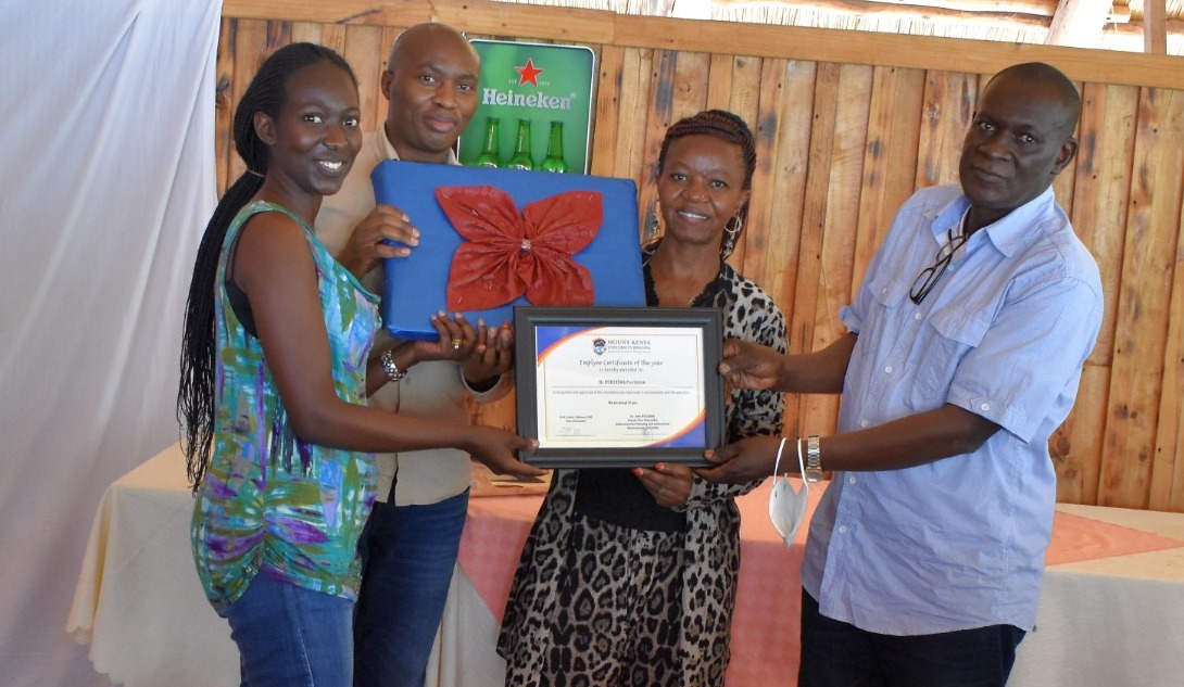 The Vice-Chancellor designate, Prof. Edwin Odhuno (right) awards a certificate of employee of the year 2021 to Providence Mukundwa (left) as the Deputy  Vice-Chancellor, Academics, Dr. Cathreen Wanjiku, and the Director of Quality Assurance, Francis Mwangi look on.