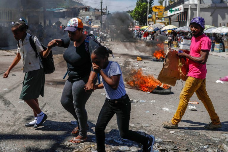 People walk past tires set fire as part of an anti-government protest in Port-au-Prince, October 21. 