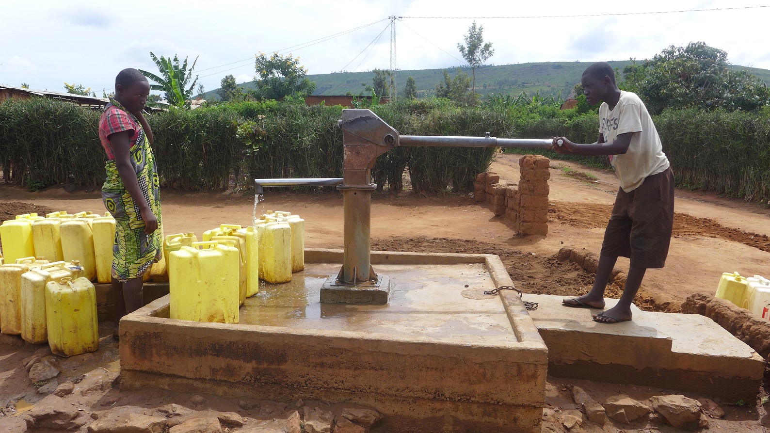 People fetch water from a borehole in rural Rwanda. Access to water is a key a part of economic development. 