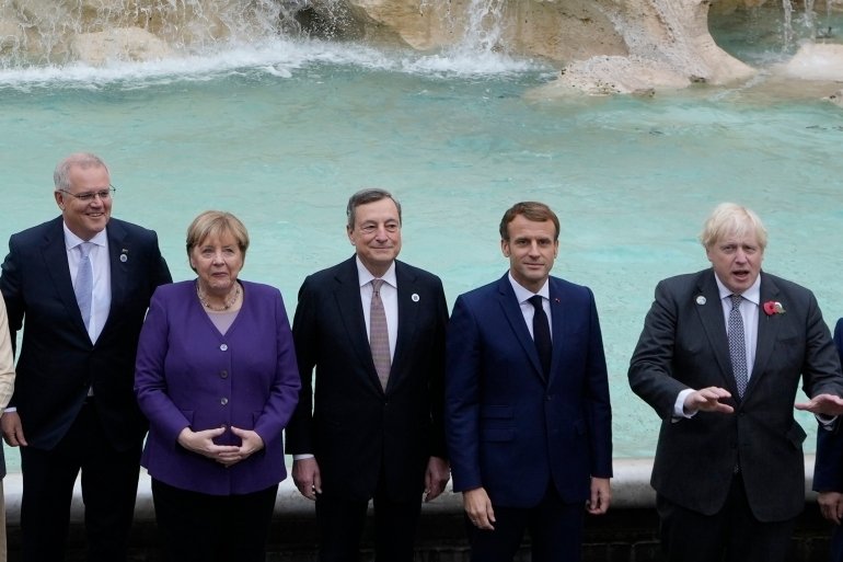 From left, Australia's Prime Minister Scott Morrison, German Chancellor Angela Merkel, Italy's Prime Minister Mario Draghi, French President Emmanuel Macron and British Prime Minister Boris Johnson pose in front of the Trevi Fountain during an event for the G20 summit in Rome, Sunday, October 31, 2021. 