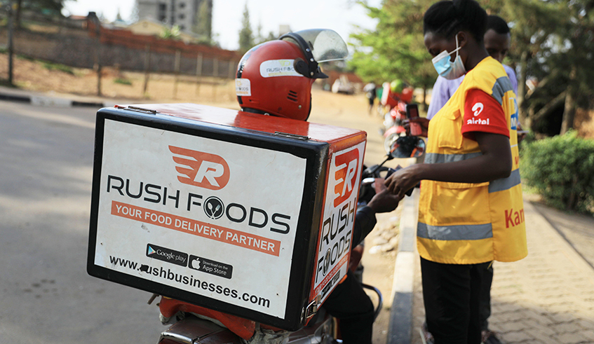 A mobile money agent provides some transactions to a motorcyclists who delivers different items shopped through e-commerce. / Photo: Sam Ngendahimana.