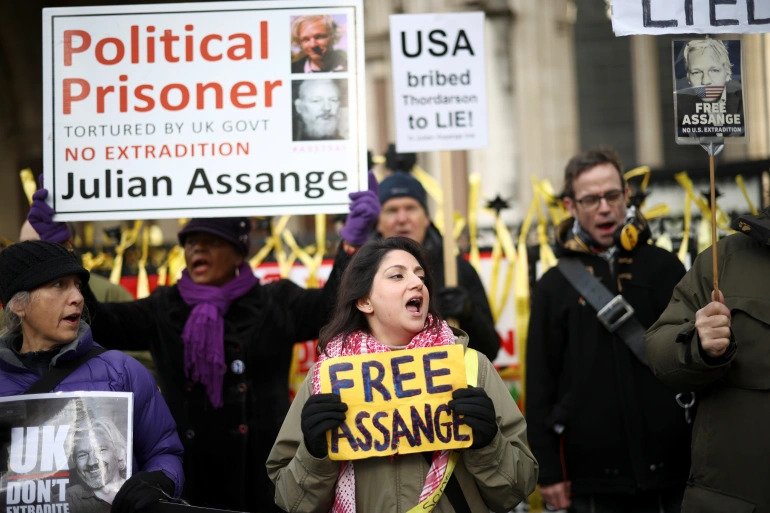 Supporters of Julian Assange hold signs outside the Royal Courts of Justice in London, Britain on December 10, 2021. 