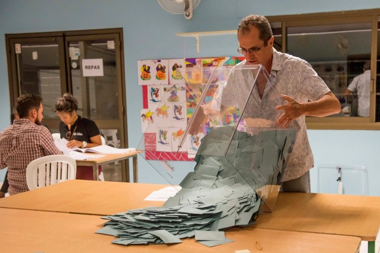 A volunteer empties a ballot box in a voting station of Noumea, New Caledonia. 