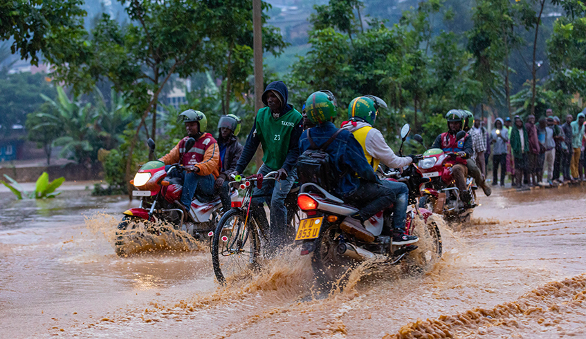Taxi moto operators go through a flooded street in Kigali in February 2020 . / File