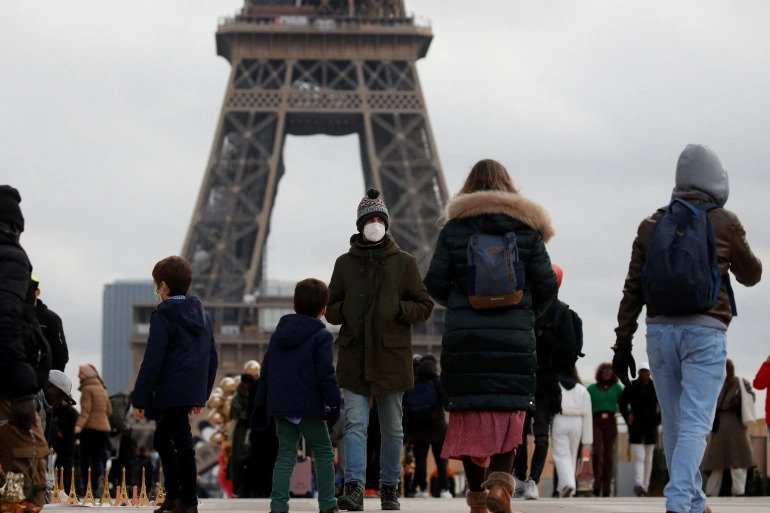 People, wearing protective face masks, walk on Trocadero square near the Eiffel Tower in Paris amid the coronavirus disease (COVID-19) outbreak in France, 