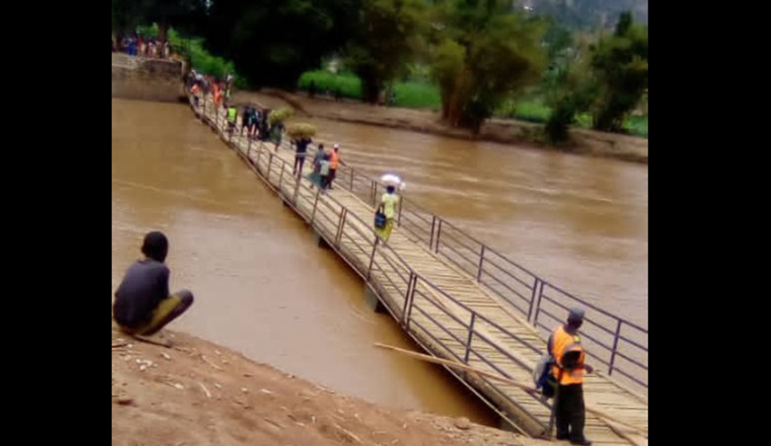 Residents cross a bridge for pedestrians that was constructed at Nyabarongo river to connect Muhanga and Gakenke Districts in Rongi Sector. It was recently destroyed by pirogue users . / Courtesy