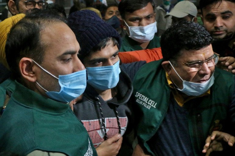 Police officials escort Niraj Bishnoi through New Delhi airport after he was arrested for allegedly creating an online app that shared pictures of Muslim women for a virtual 'auction'. 