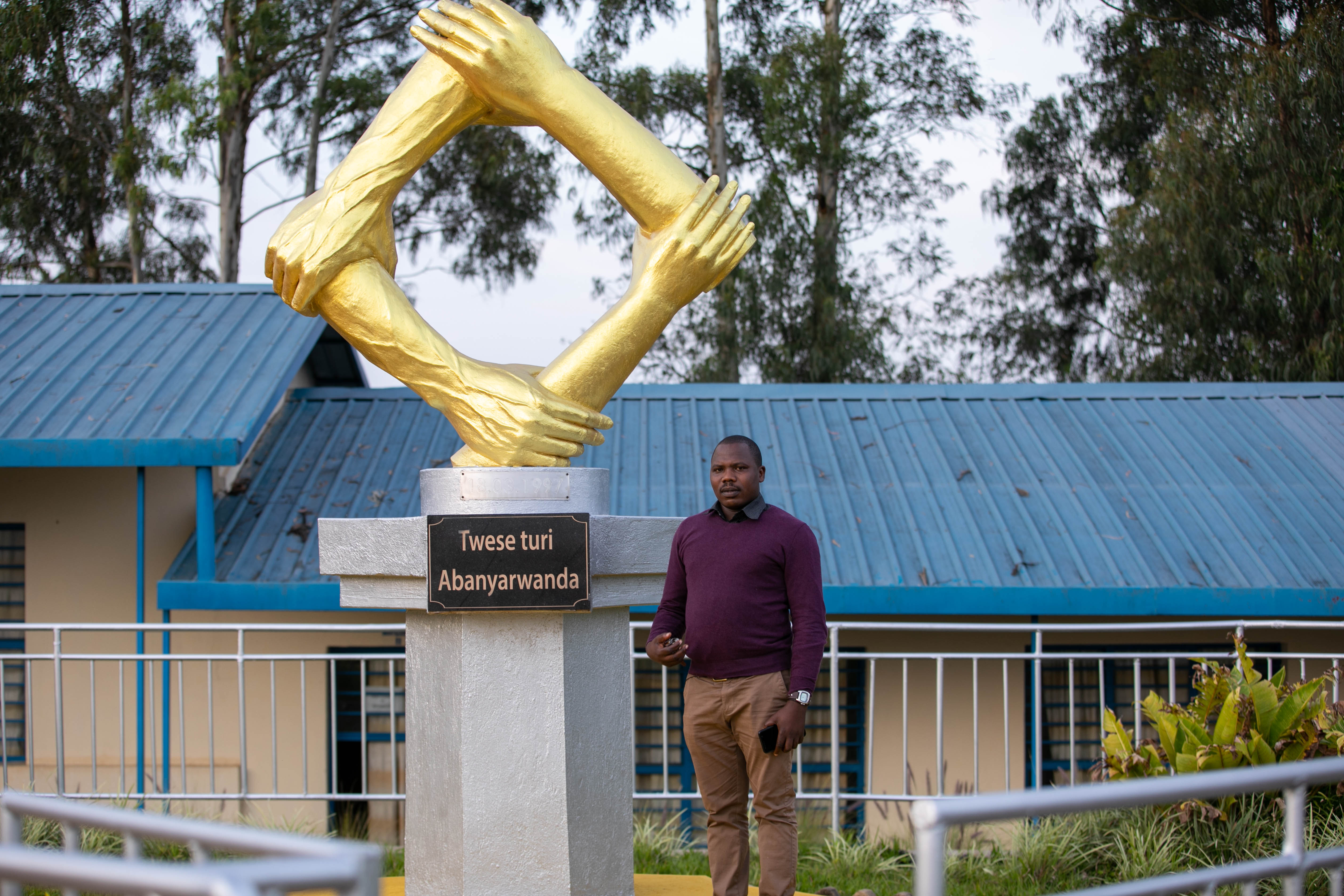ES Nyange head teacher, Father Rene Claude Hakizimana, in front of the monument installed in honour of the extraordinary courage and heroism that characterised the schoolu2019s Senior Six and Five students a quarter century ago. 