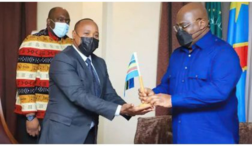 EAC Secretary General, Peter Mathuki (Left), hands the East African Community flag to DR Congo President, Fu00e9lix Tshisekedi, in the Congolese city of Goma in June 2021, as the latter launched the verification mission for his country's bid to join the Community.