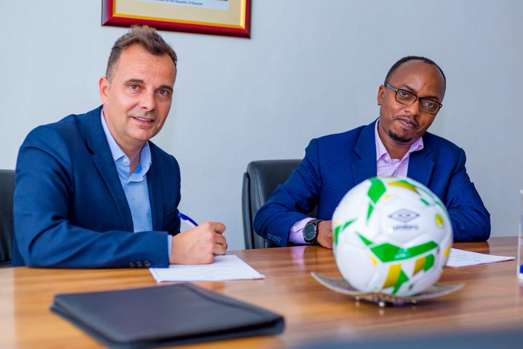 Carlos Alu00f3s Ferrer, the new Head Coach of Amavubi (L) signs a one year deal to coach the national side on Tuesday. On the right is Henry Muhire, the Secretary General of Ferwafa. Photo: Ferwafa.