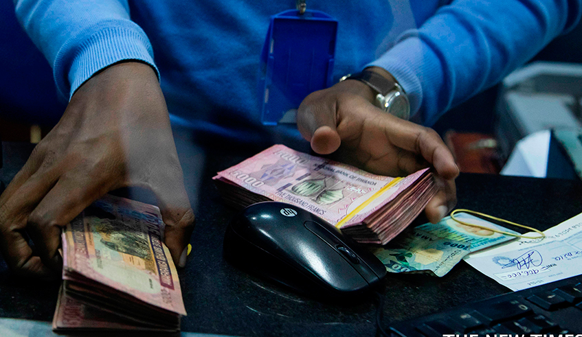 A bank teller counts money while serving customers at Bank of Kigali head office. / Dan Nsengiyumva 
