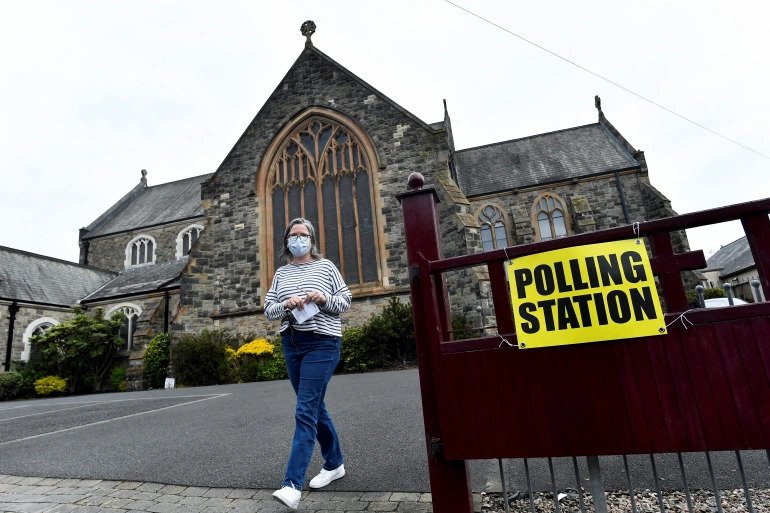 A woman walks outside a polling station in St Peter's Church of Ireland on the day of the Northern Ireland Assembly elections in Belfast. 