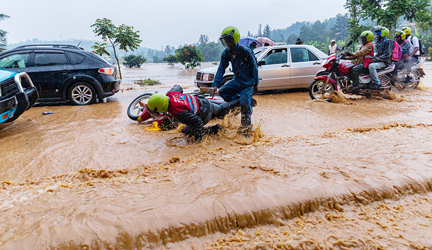 Road users wade through a flooded street in Kigali on January 28, 2020. Rwanda could soon host a publicly accessible data centre on weather, climate, air pollution and water resources to serve the needs of governmental. / File