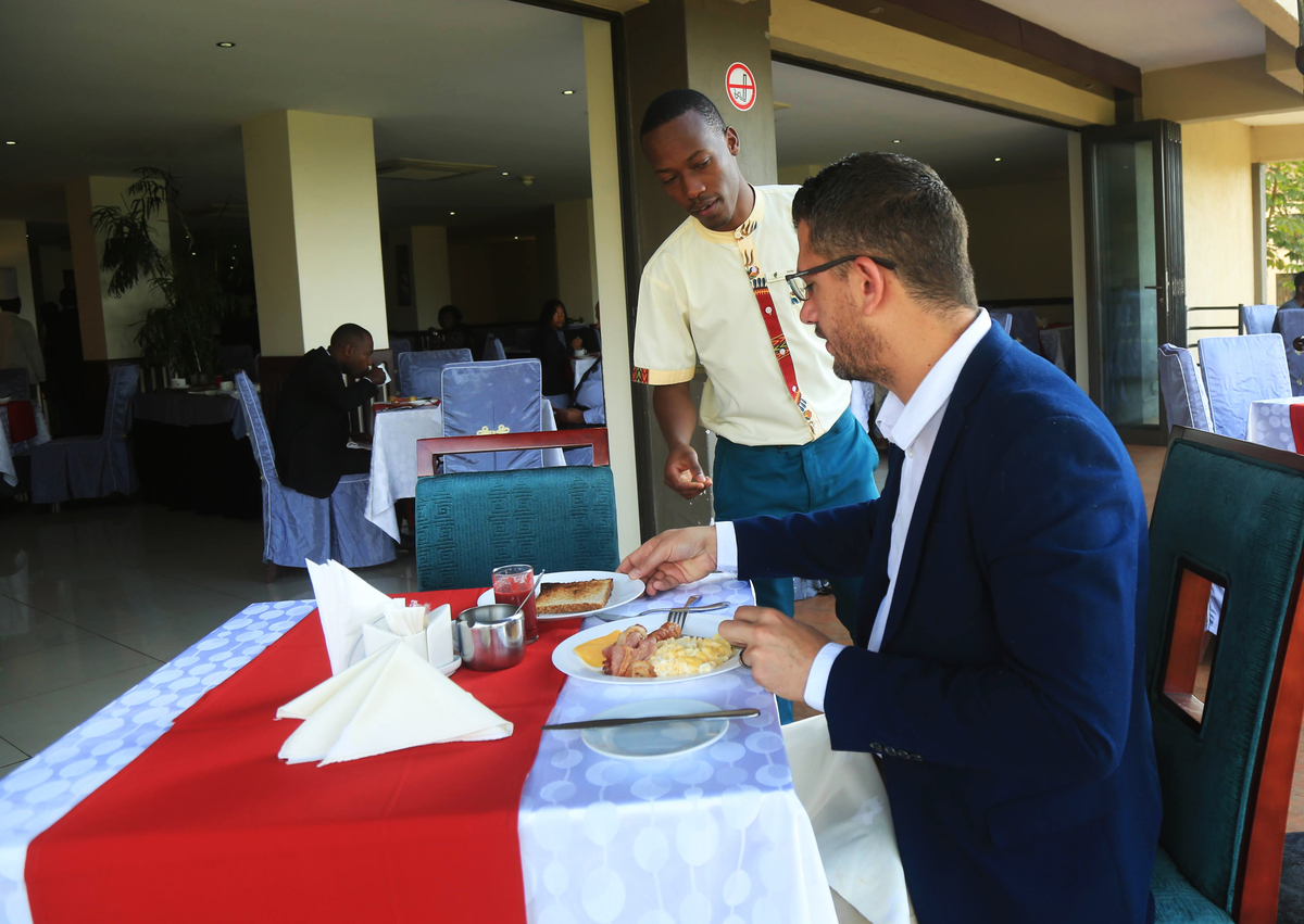 A waiter serves a customer during the breakfast at Portofino Hotel in Kigali. 