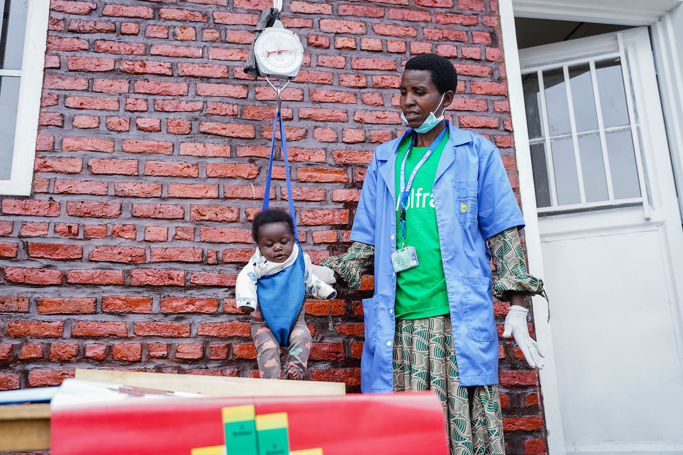 A Community Health Worker weighs a child at an Early Childhood Development centre. Photos: Dan Nsengiyumva.