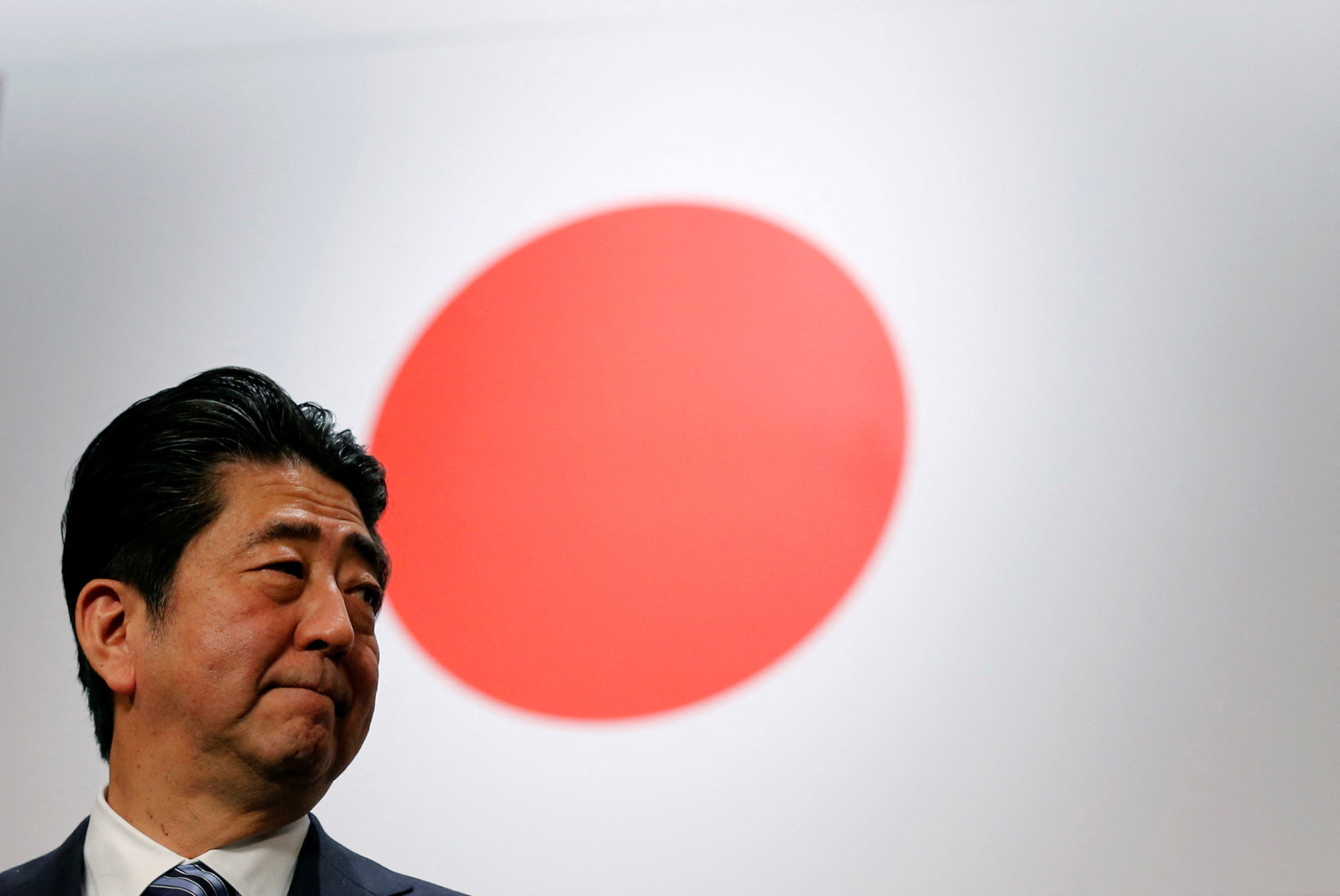 Then-Prime Minister Shinzo Abe stands in front of Japan's national flag after his ruling Liberal Democratic Party's (LDP) annual convention in Tokyo on March 5, 2017. 