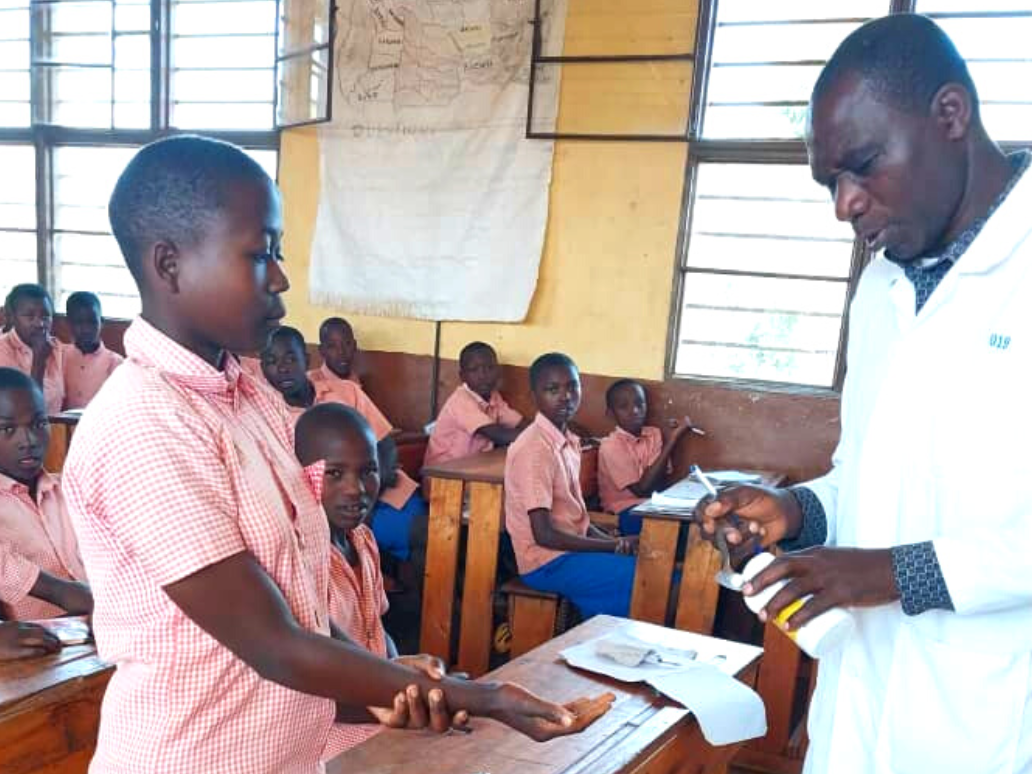 A teacher giving a tablet to his student at Groupe Scolaire Giheke, Rusizi District.