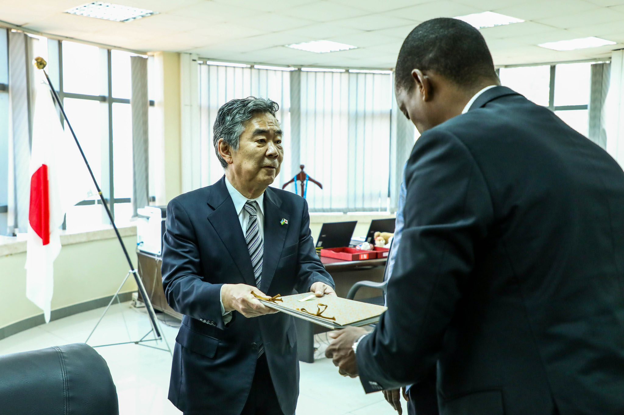 Amb. Masahiro IMAI, Japanese envoy to Rwanda, hands over the book of condolences to Eddy Sebera, Greenleaf Motors Board Chair, in Kigali on July 14. Photo: Dan Nsengiyumva.