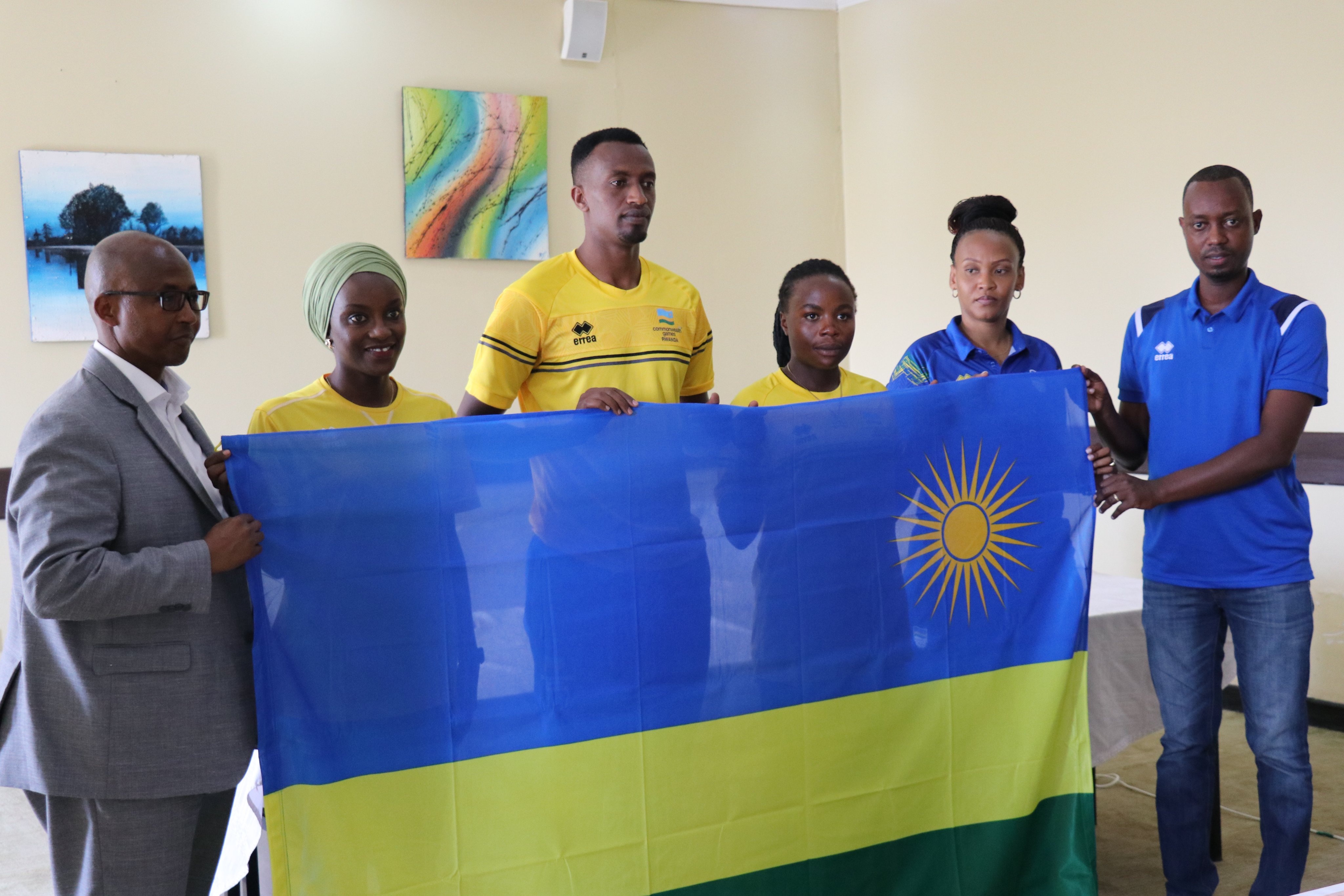 Olivier Ntagengwa (C) is presented with the Rwandan flag as he leads fellow athletes to the Birmingham 2022 Games. 