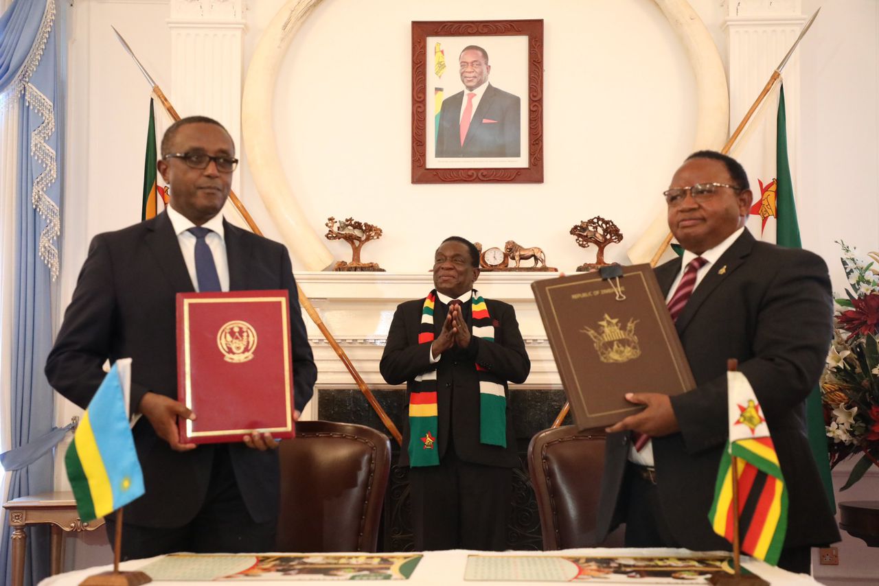 Rwanda's Minister for Foreign Affairs and International Cooperation, Vincent Biruta (left), and his Zimbabwean counterpart Frederick Shava sign pacts that include an Extradition Treaty, a Memorandum of Understanding on Immigration Cooperation, and another one on cooperation in investigating civil aircraft accidents and serious incidents while President Emmerson Mnangagwa of Zimbabwe (background) looks on, at State House in Harare, on July 29. 