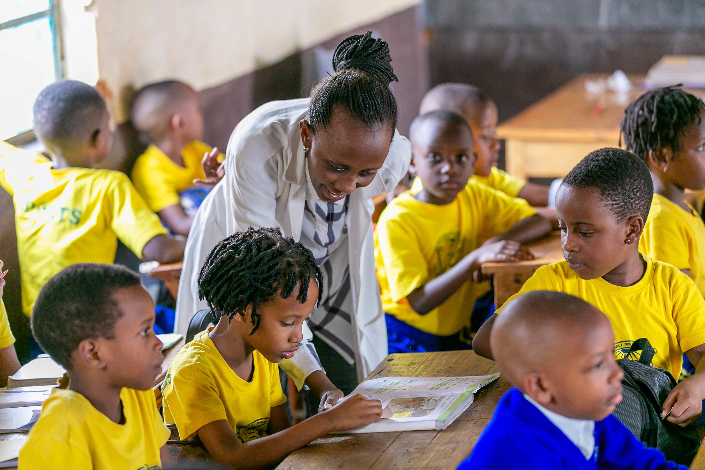 A primary school teacher helps pupils during a class at Groupe Scolaire Camp Kigali in 2019. While presenting the Government activities in basic education under the National Strategy for Transformation  to both Chambers of Parliament, Prime Minister Edouard Ngirente announced  the decision to raise teachersu2019 pay after considering teachersu2019 financial means, welfare and the link between that and the quality of education. File