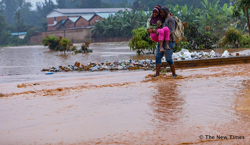 Pedestrians wade through a flooded wetland in Kigali on January 28, 2020. more than 745,000 hectares of agricultural land in Rwanda potentially loses its topsoil every year . File