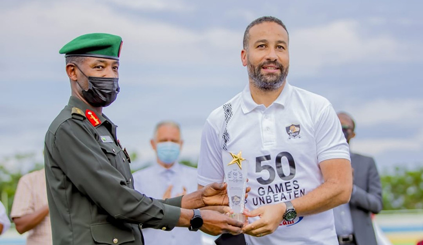 APR chairman, Lt. Gen. Mubarakh Muganga (L), hands an award to head coach Adil Erradi after the Moroccan tactician guided the club to 50 matches unbeaten last season. Photo: File.
